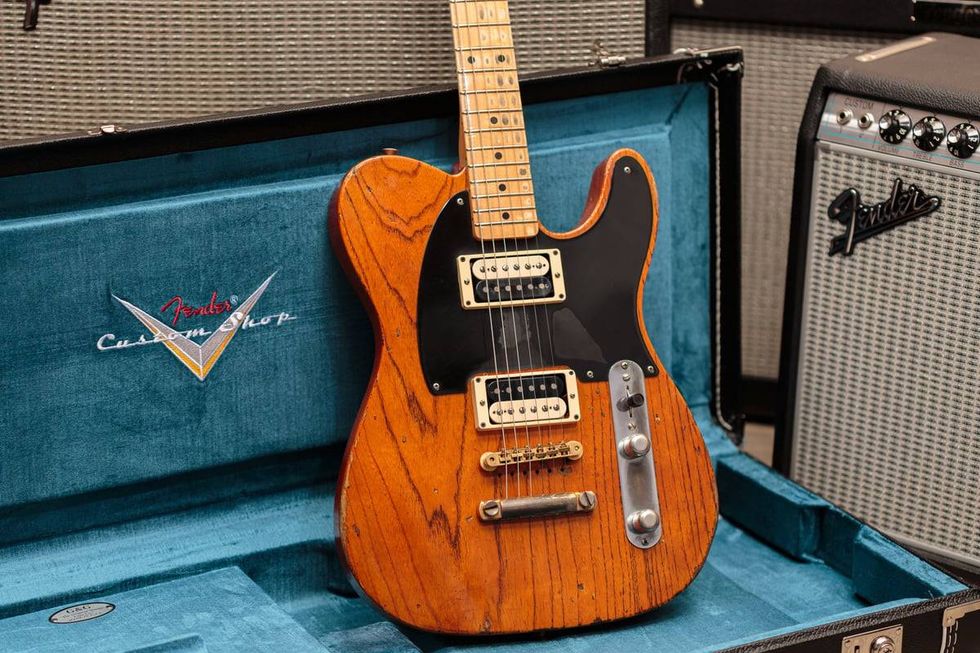 Fender Custom Shop guitar in a blue velvet case, with amplifiers in the background.