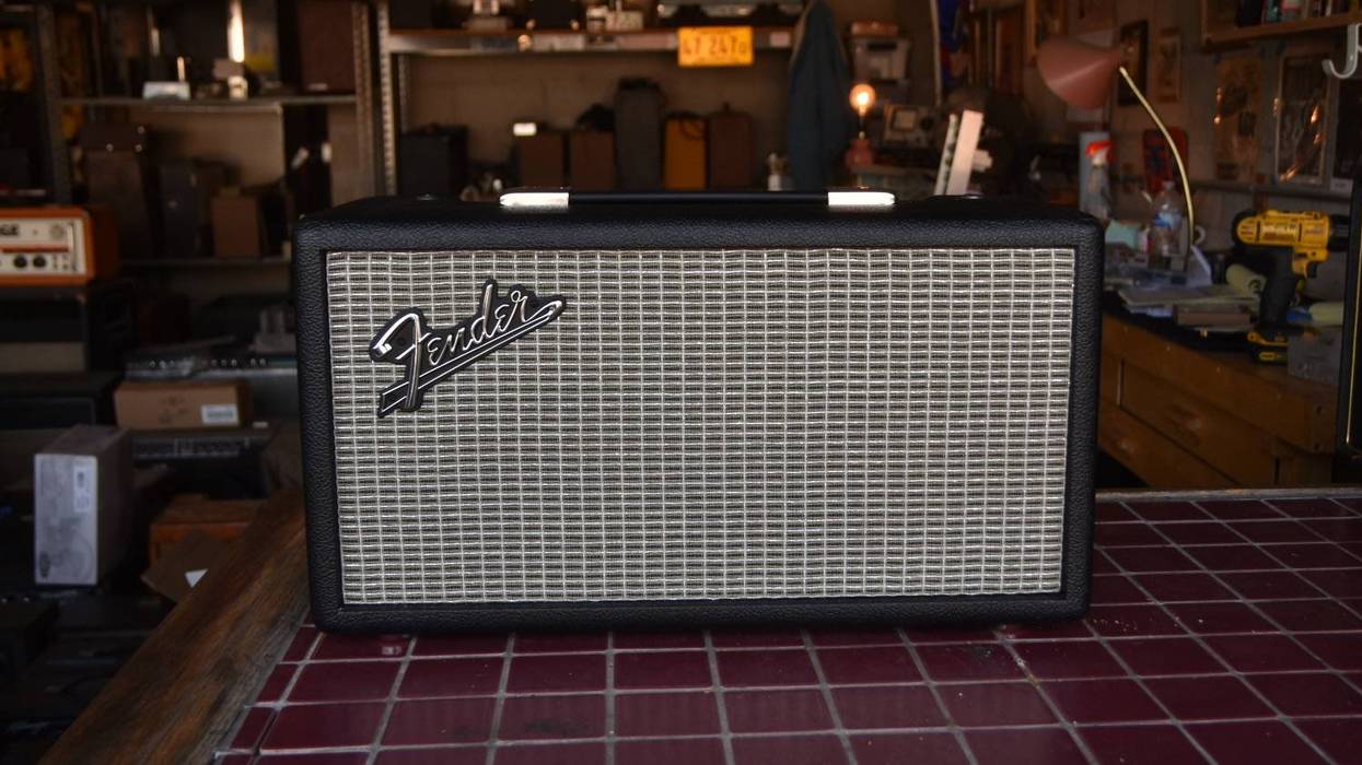 Fender speaker on a table, with vintage decor in the background.