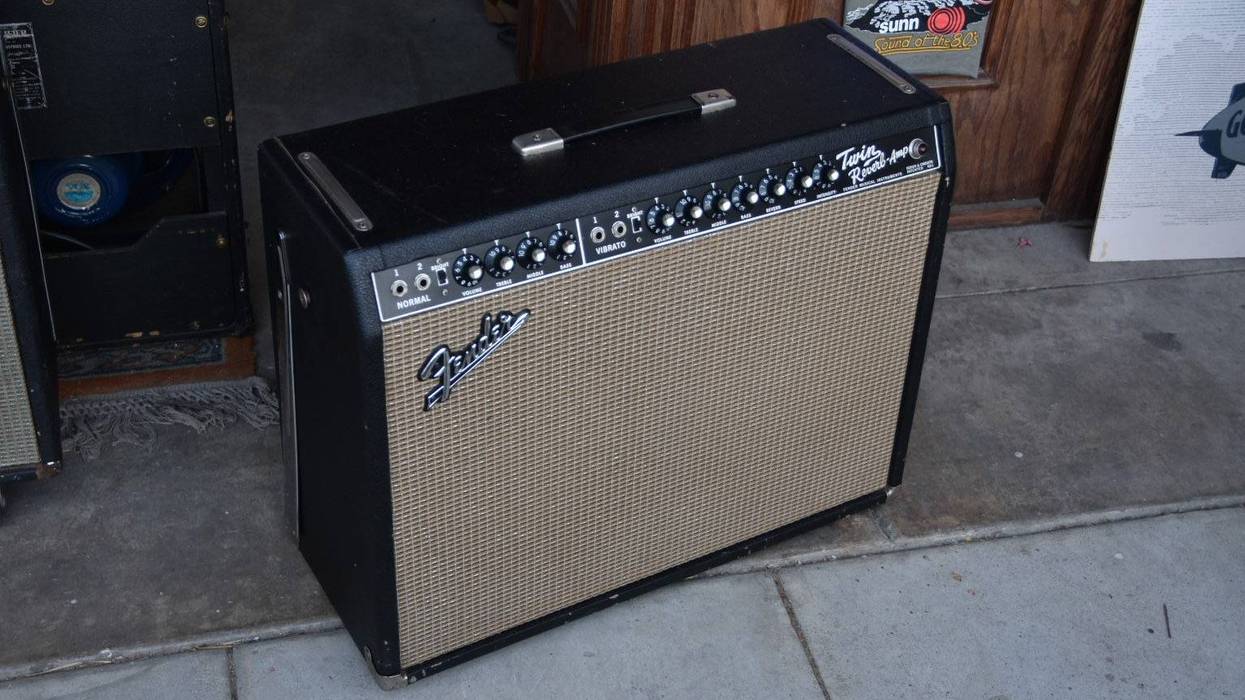 Fender Twin Reverb guitar amplifier on a concrete surface with a wooden background.