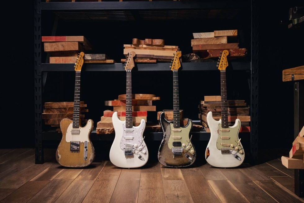 Four electric guitars in a row, displayed on a wooden shelf with scattered wood blocks.