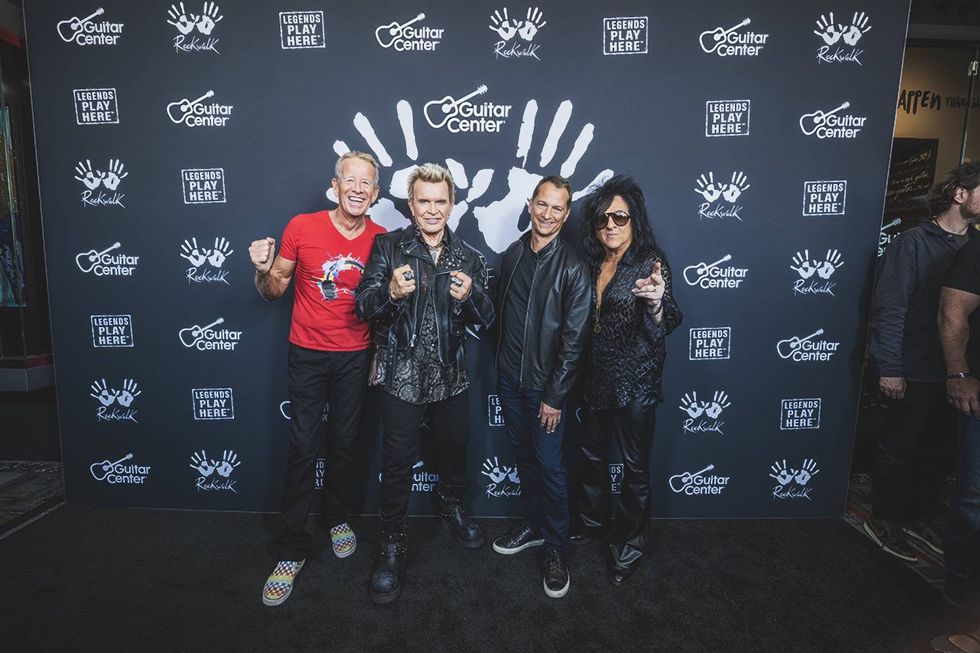 Four musicians pose in front of a Guitar Center backdrop, celebrating their legacy.