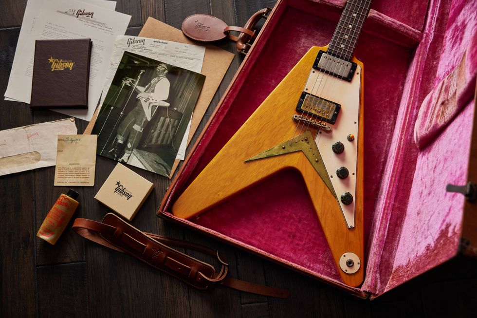 Gibson guitar in pink velvet case, surrounded by documents and memorabilia.