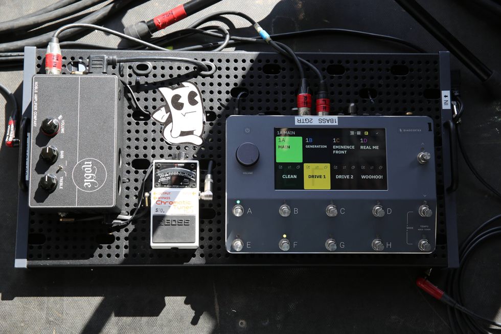 Guitar pedalboard featuring various effects, tuner, and digital display panel.