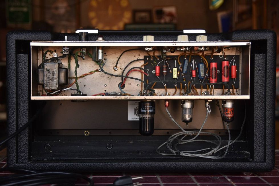 Interior view of a vintage guitar amplifier with exposed wiring and tubes.