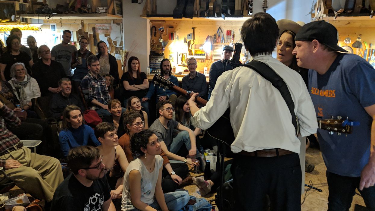 Intimate music performance with a captivated audience in a cozy, instrument-filled space.
