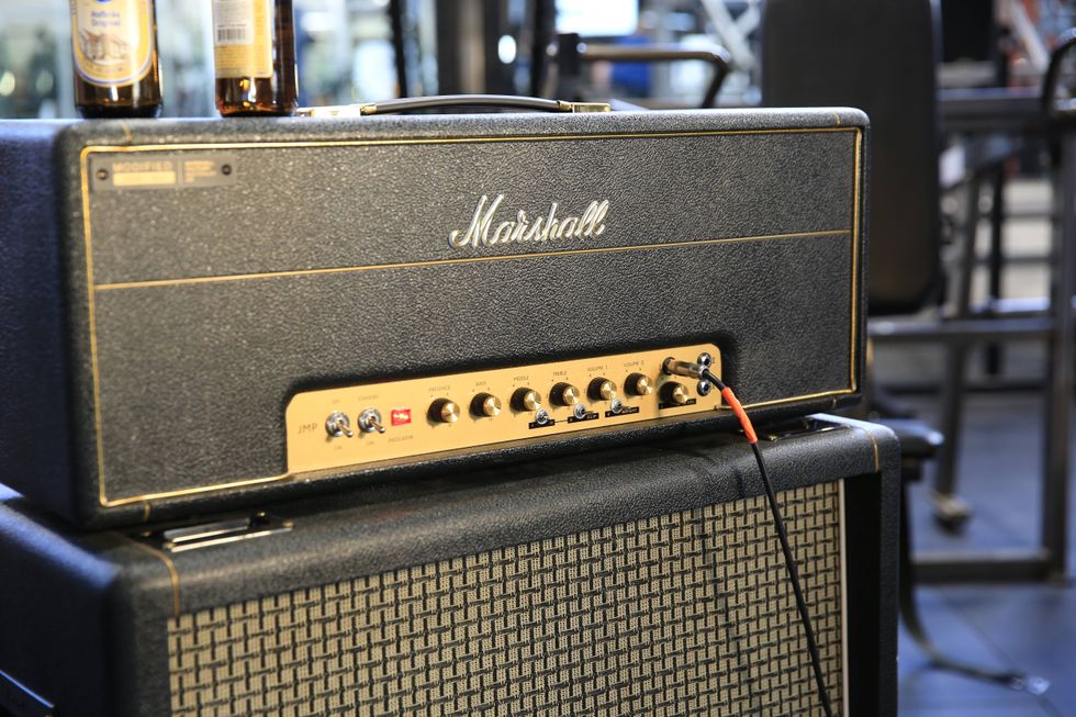 Marshall guitar amplifier stacked on speaker cabinet, with two bottles in the background.