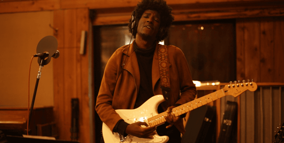 Musician in recording studio playing electric guitar with a passionate expression.