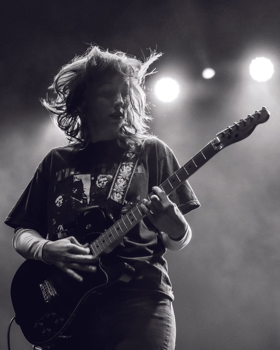 Musician playing electric guitar passionately on stage with dynamic lighting.