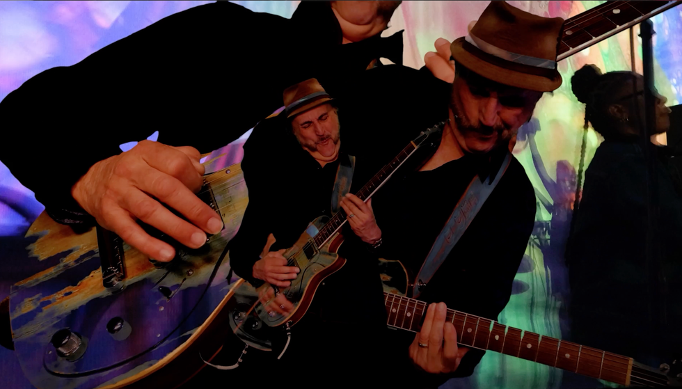 Musician playing guitar with vibrant, abstract visuals in the background.