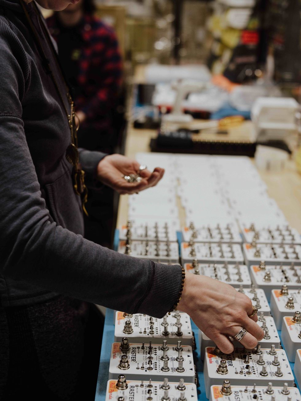 Person assembling electronic devices on a workbench, focusing on detailed components.