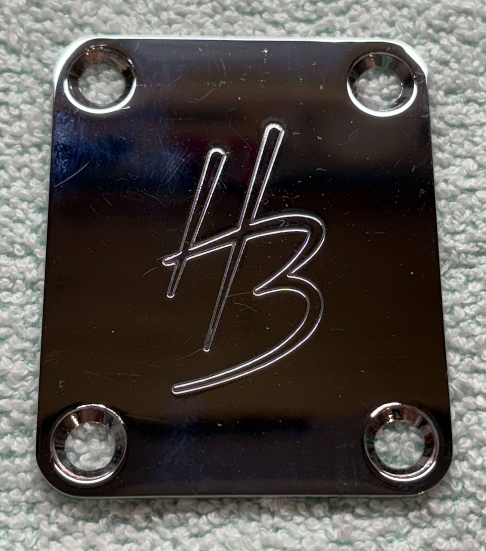 Polished metal plate engraved with "HB," featuring four mounting holes.