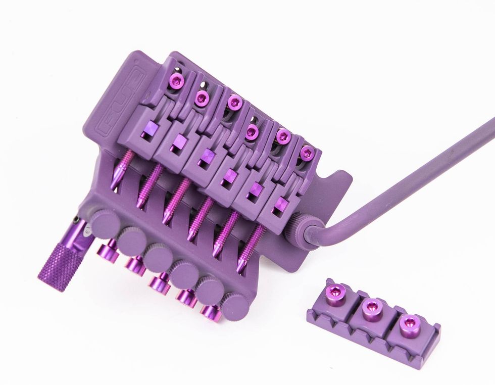 Purple guitar bridge with tuning screws and additional mounting plate beside it.