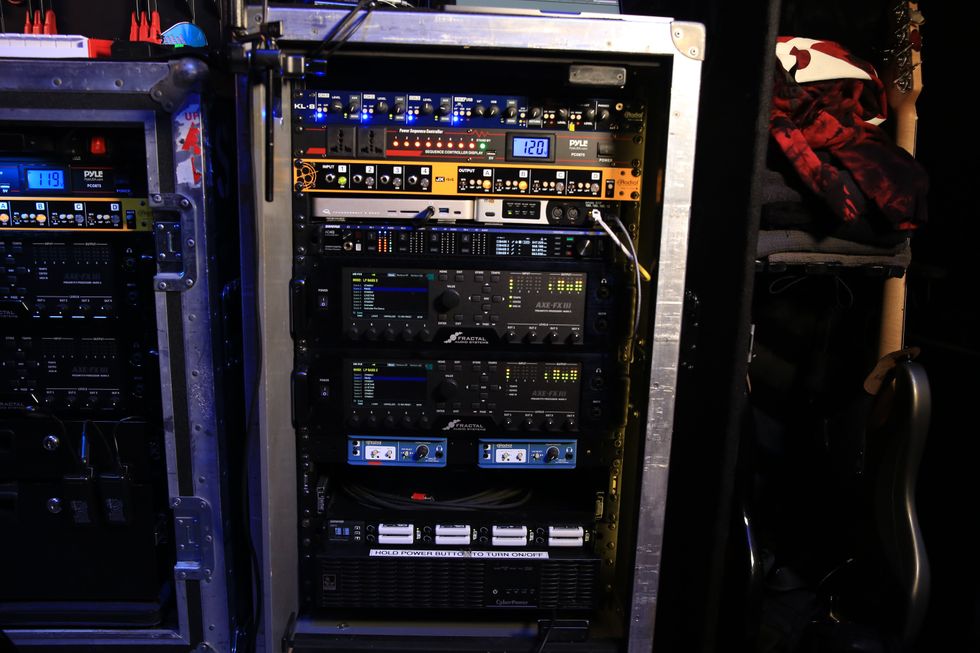 Rack-mounted audio equipment with various processors and cables in a dimly lit setting.