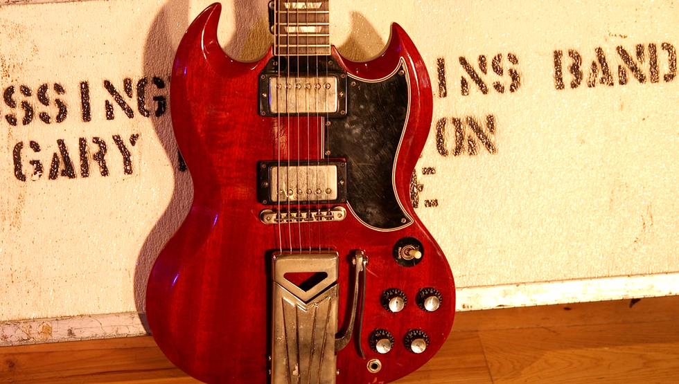 Red electric guitar with a stylish body, set against a textured white background.