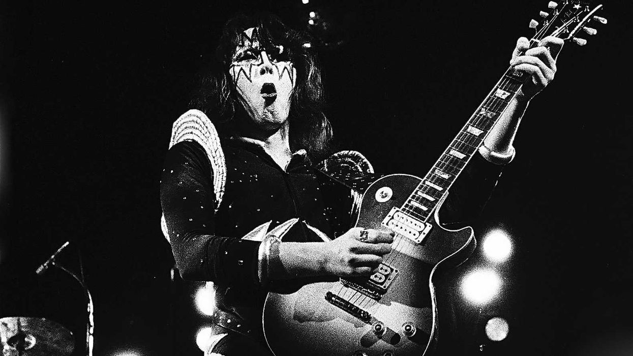 Rock musician in stage makeup passionately plays an electric guitar with dramatic lighting.