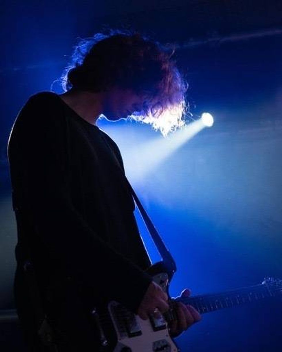 Silhouette of a guitarist under dramatic blue stage lighting.
