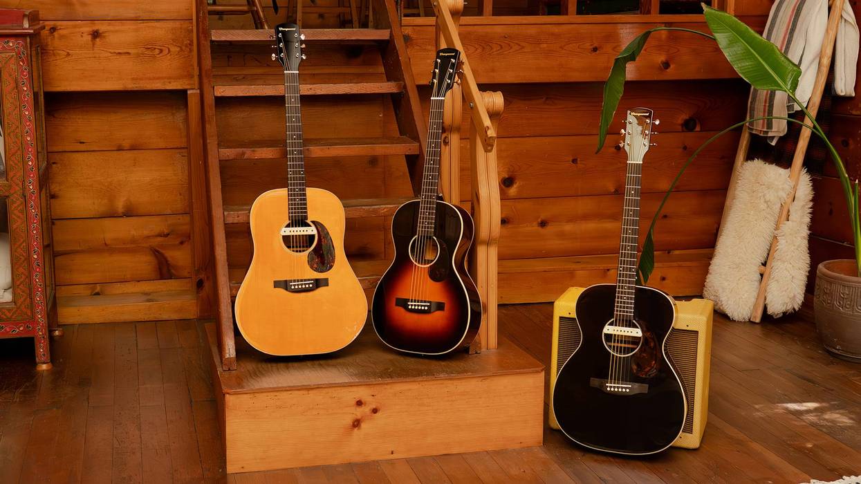 Three acoustic guitars of various sizes rest on wooden steps in a cozy cabin setting.