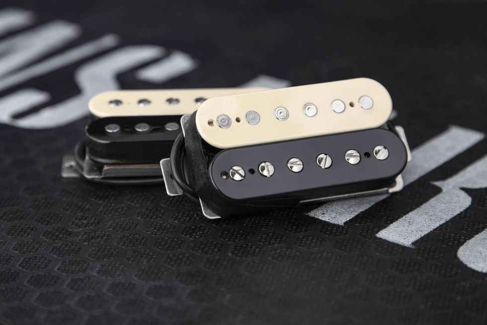 Three guitar pickups in black and cream colors, resting on a textured black surface.