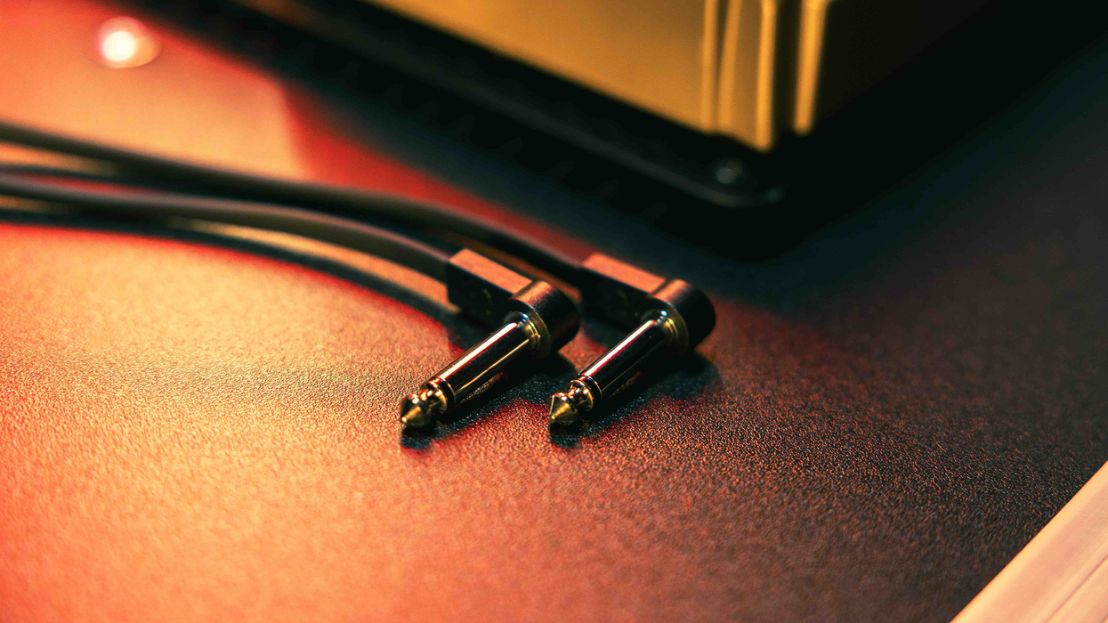 Two audio jacks with black cables resting on a textured surface.