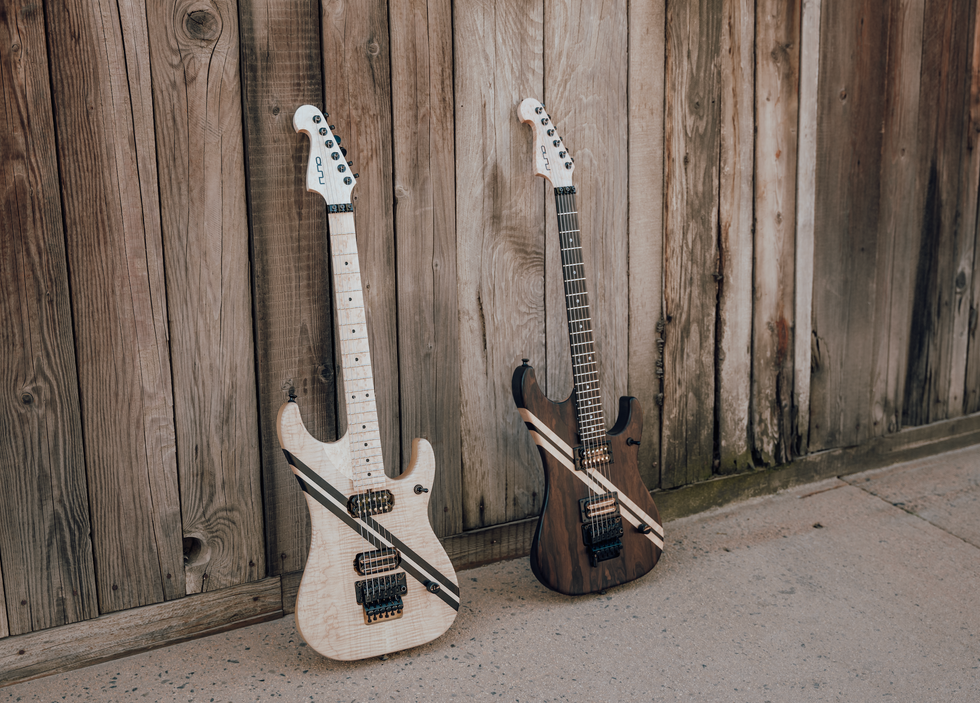 Two electric guitars lean against a wooden wall, showcasing their unique designs.