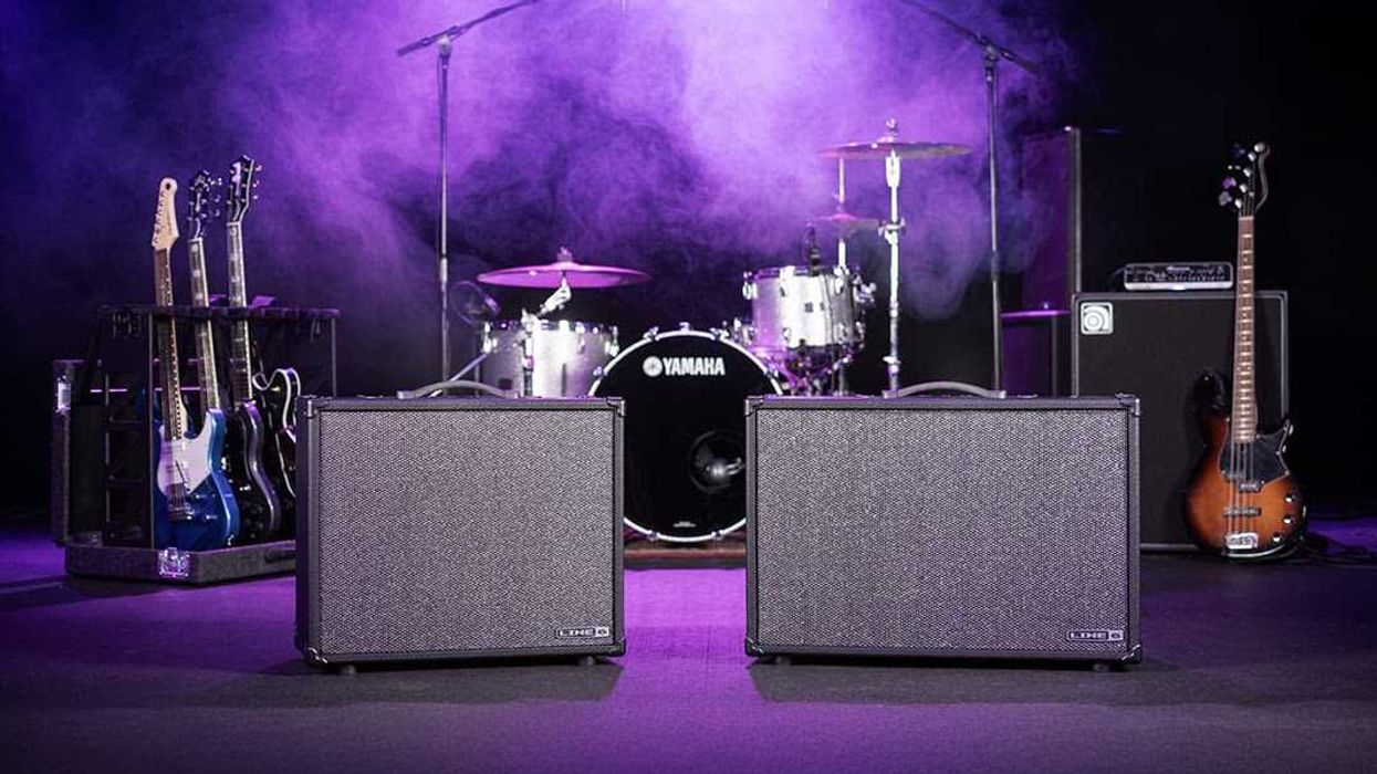 Two guitar amplifiers in front of a drum set and electric guitars on a colorful stage.