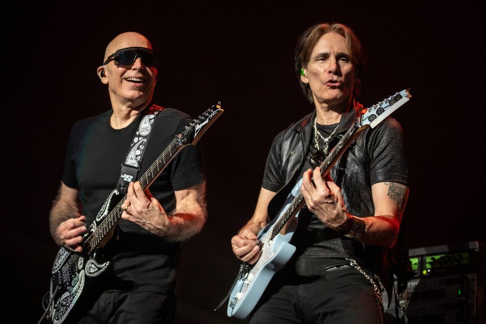 Two guitarists perform on stage, showcasing their skills with electric guitars.