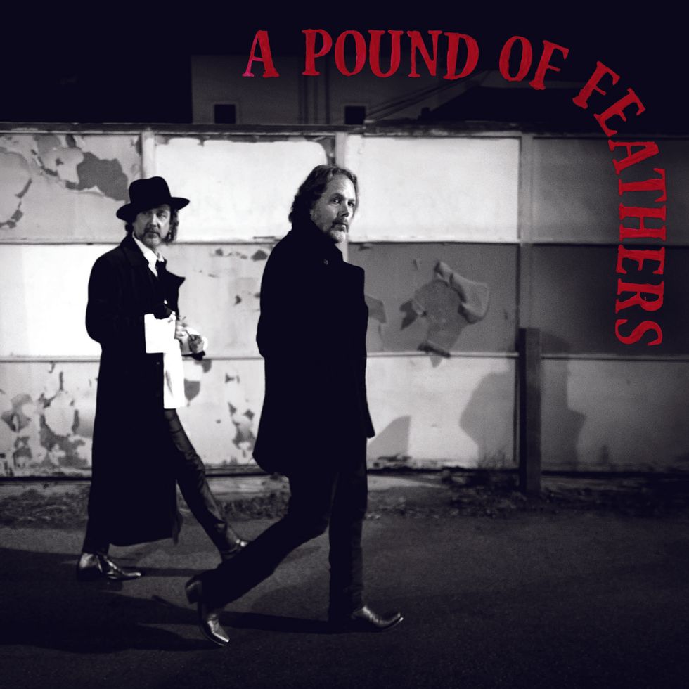Two men in dark coats walking past a peeling wall, with "A Pound of Feathers" title above.