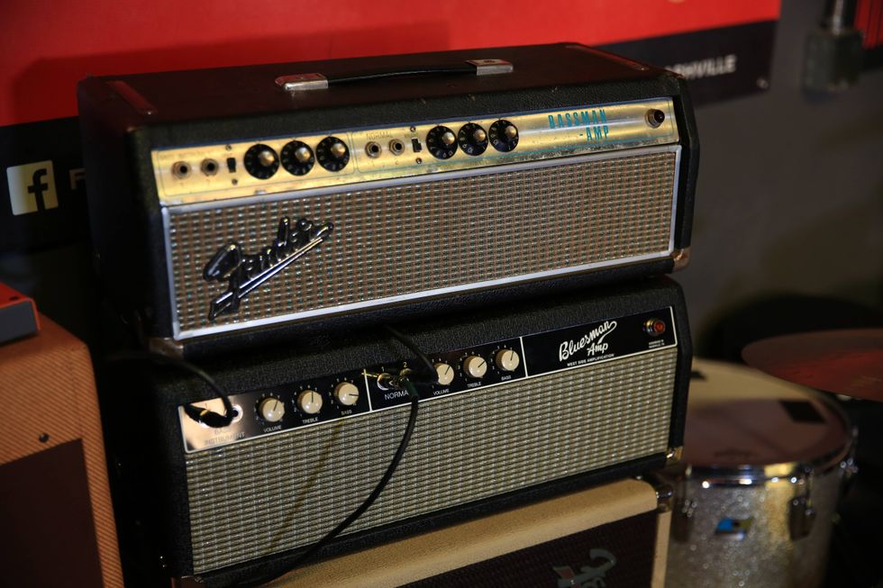 Two vintage guitar amplifiers stacked, featuring knobs and metal grilles, against a colorful background.