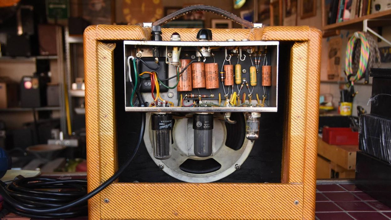 Vintage amplifier showing internal circuitry with tubes and components against a textured exterior.