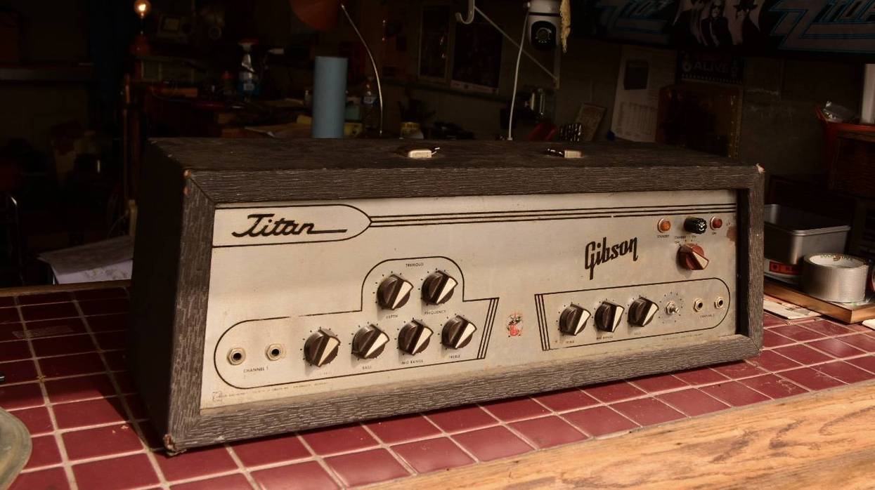 Vintage Gibson Titan amplifier on a tiled surface, surrounded by workshop items.