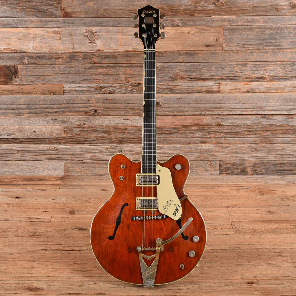 Vintage Gretsch guitar with a sunburst finish, set against a wooden background.