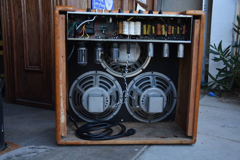 Vintage guitar amplifier showing internal components and two large speakers.