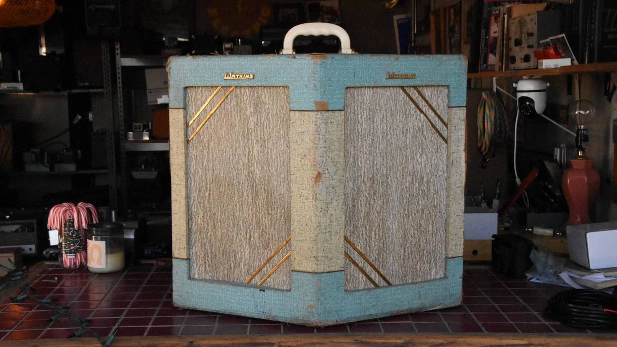 Vintage guitar amplifier with a turquoise and beige design on a wooden table.