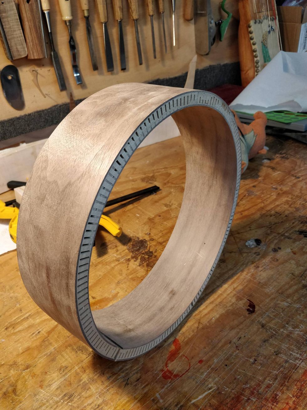Wooden ring with marked edges, set on a workbench surrounded by tools.
