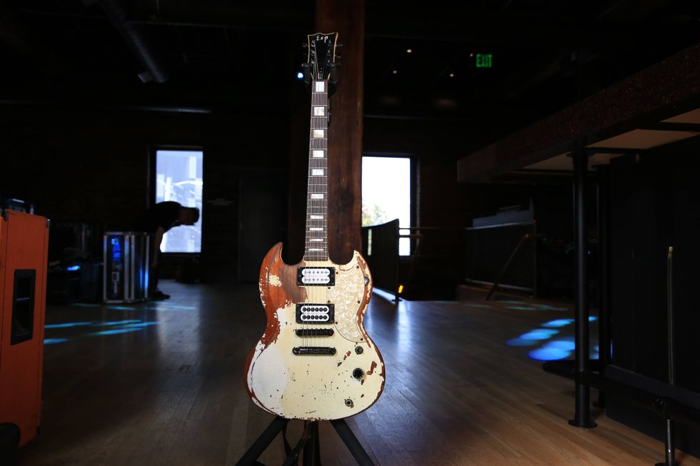 Worn electric guitar on a stand in a dimly lit music venue.